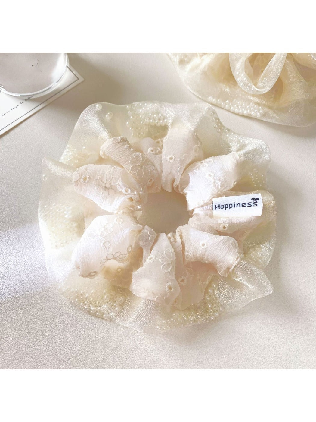 White tulle scrunchie with ruffled edges shown from a side angle