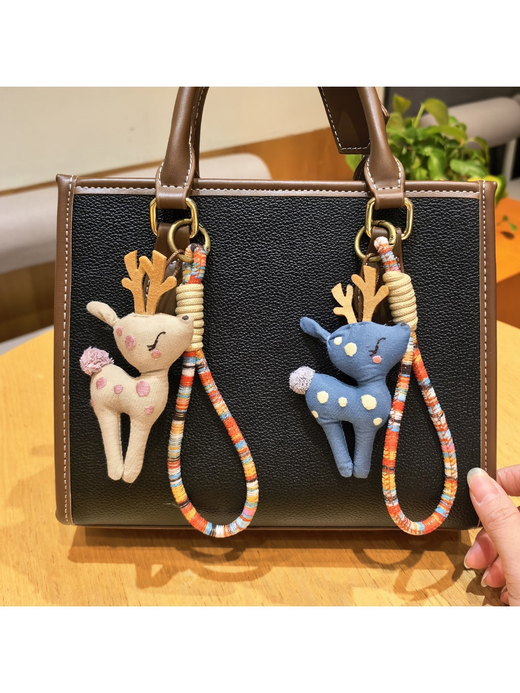 Deer charm keychain hanging from a set of keys on a wooden surface