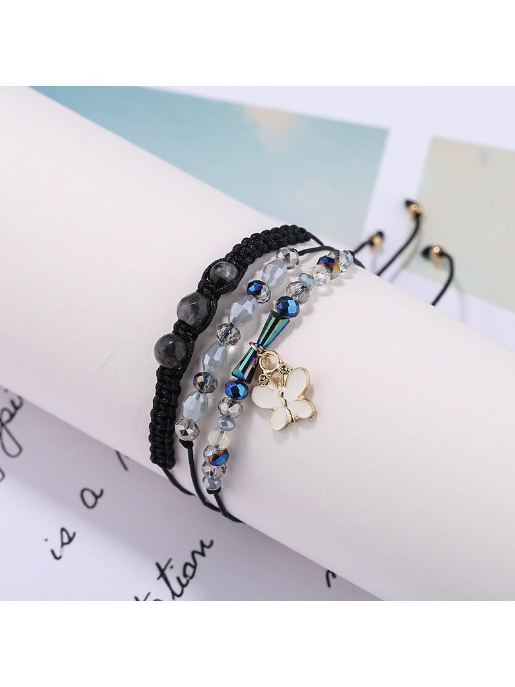 Lovra bracelet with butterfly pendant worn on wrist alongside other bracelets