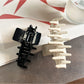 Beau claw clip holding hair, showcasing rhinestone accents and glossy acetate finish