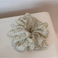 Gifty scrunchie laid flat next to a matching daisy print accessory