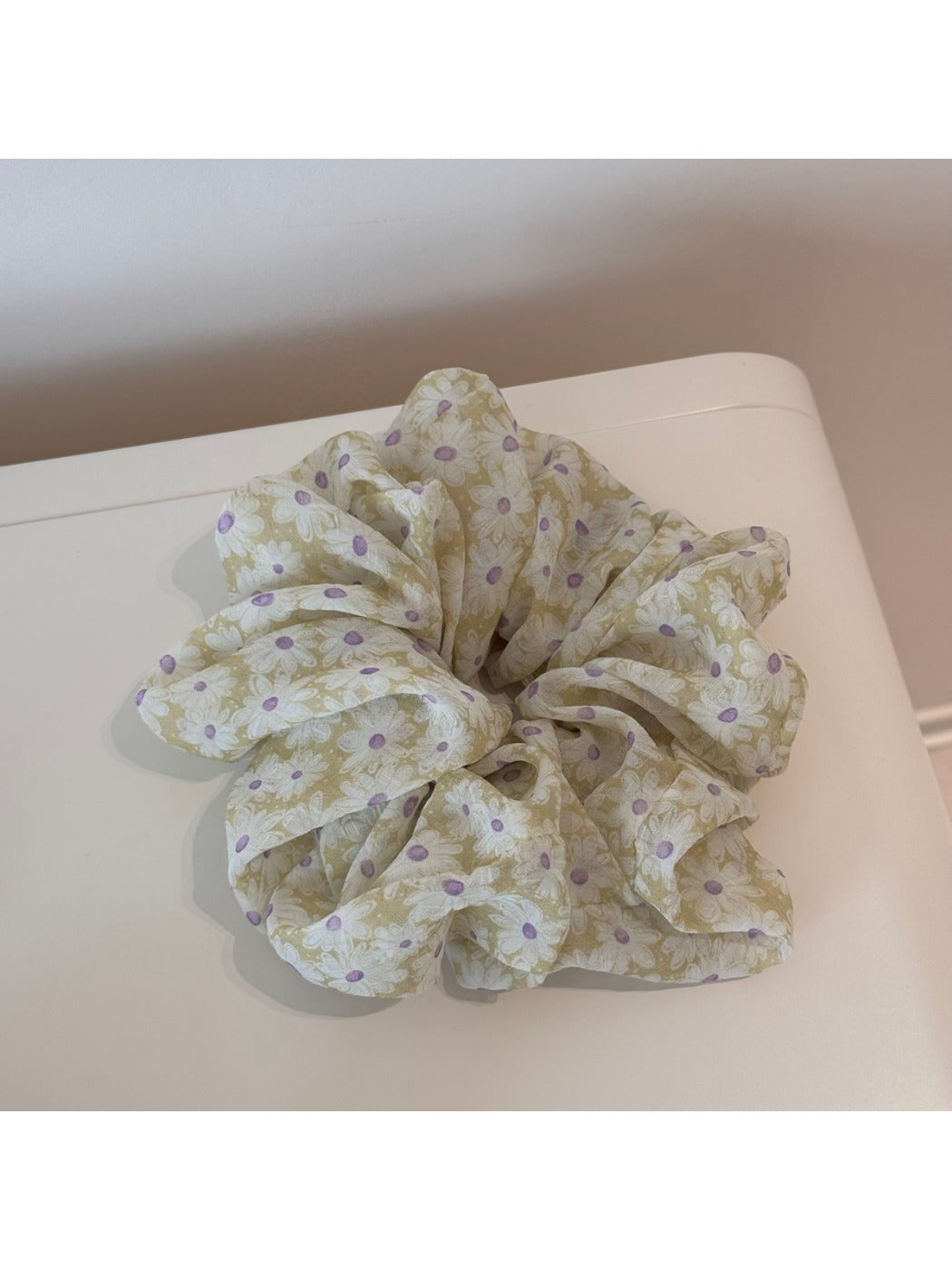Gifty scrunchie laid flat next to a matching daisy print accessory