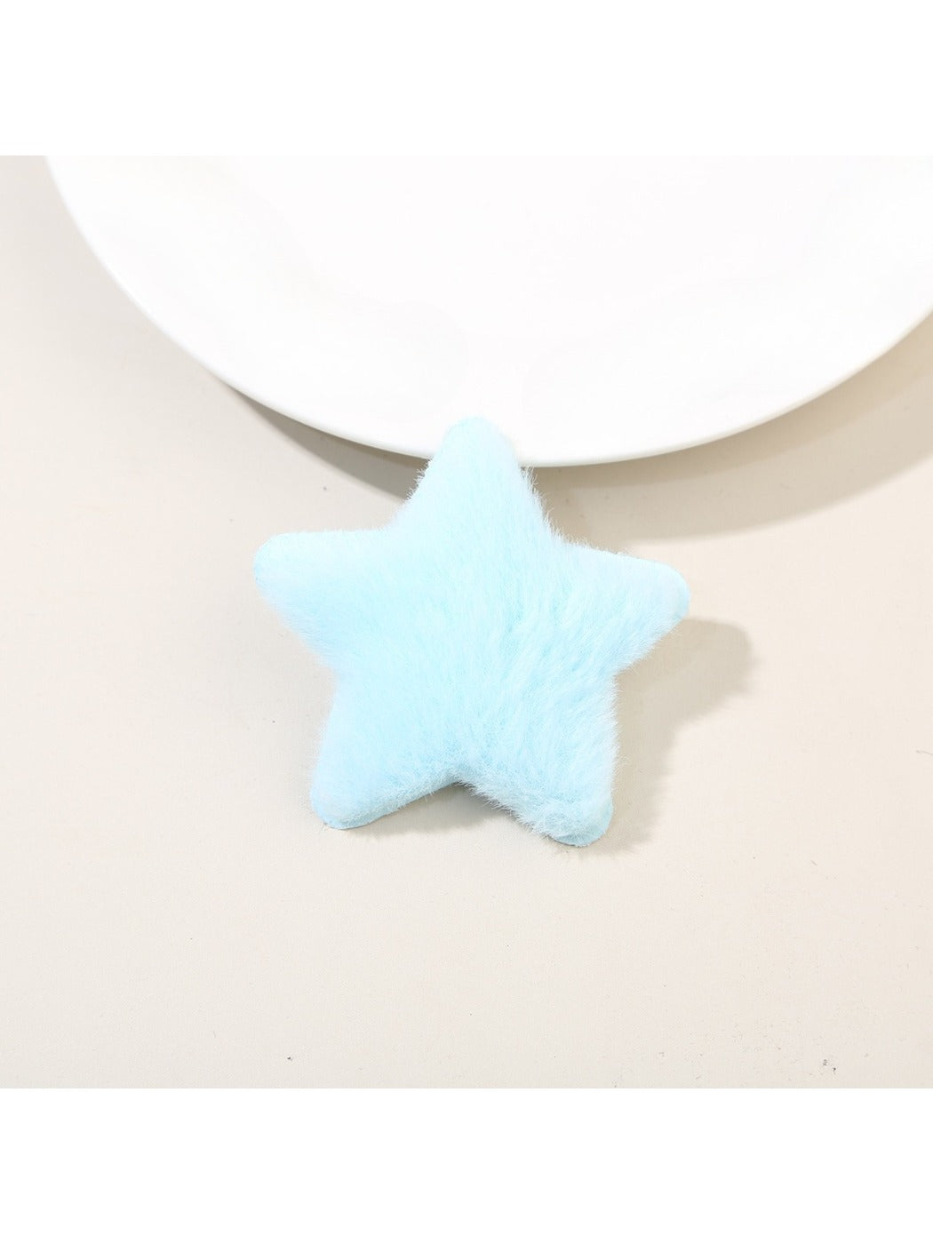 Plush star hair clip resting on a wooden surface with natural lighting