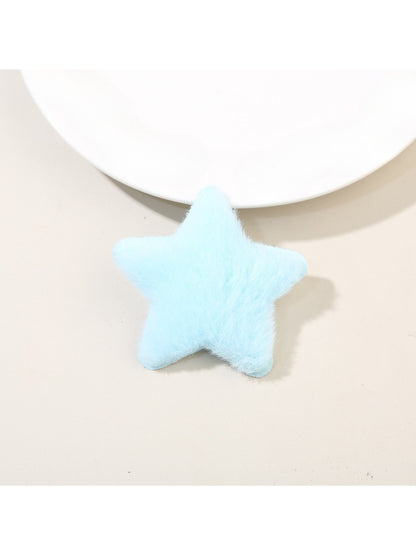 Plush star hair clip resting on a wooden surface with natural lighting