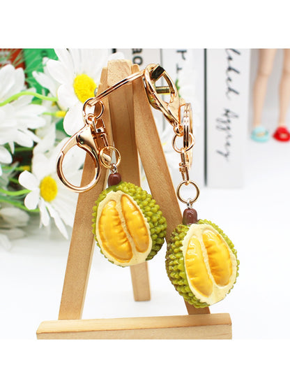 Durian keychain hanging from a set of keys on a wooden surface