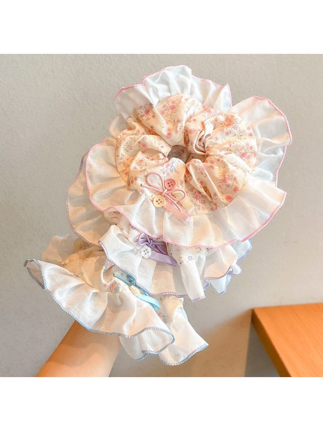 Gifty floral scrunchie stretched around a wrist showing its elasticity and floral pattern