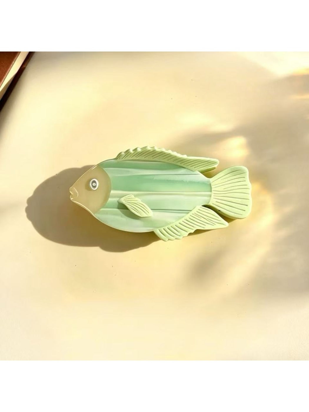 Beau fish shape claw clip in pastel blue displayed on a wooden surface