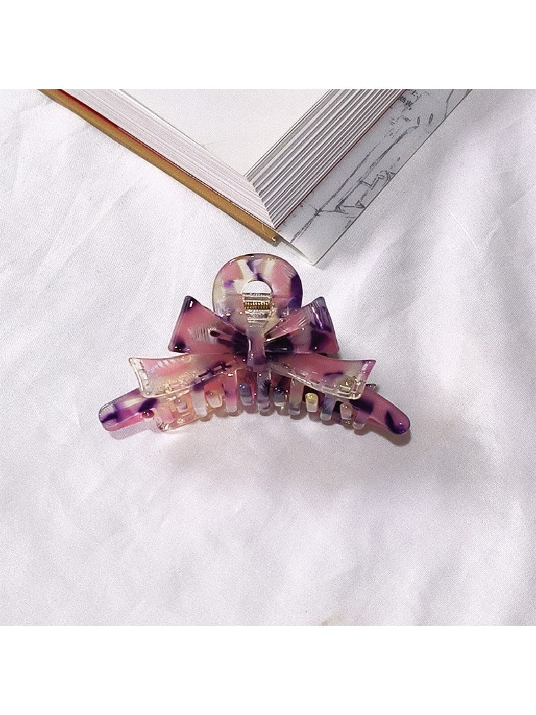 Beau acetate bow shaped claw clip resting on reflective surface