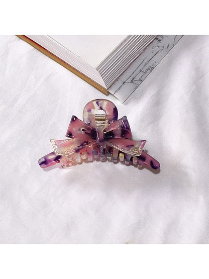 Beau acetate bow shaped claw clip resting on reflective surface
