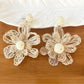 Earedge raffia flower shaped drop earrings displayed on wooden surface