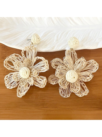 Earedge raffia flower shaped drop earrings displayed on wooden surface