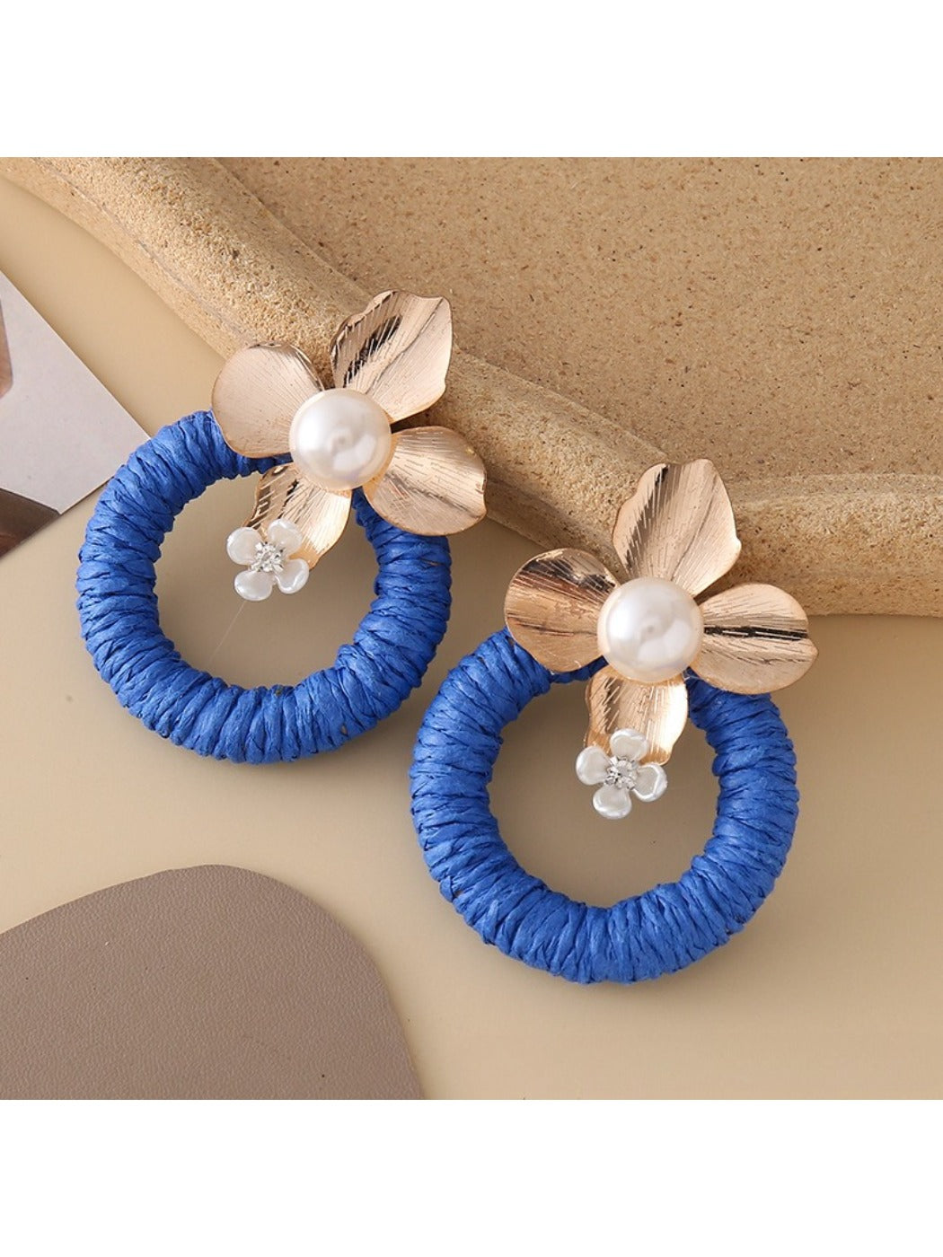 Earedge round floral pendant earrings hanging from a jewelry stand