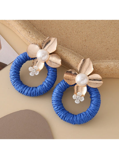 Earedge round floral pendant earrings hanging from a jewelry stand