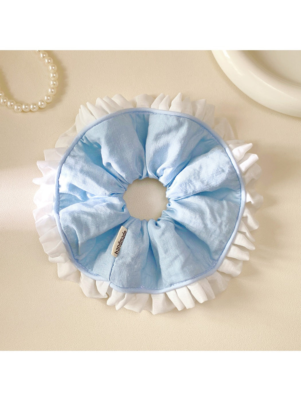 White and blue ruffle scrunchie displayed on a white surface