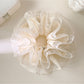 White lace multi-layer scrunchie with delicate floral pattern on a plain background