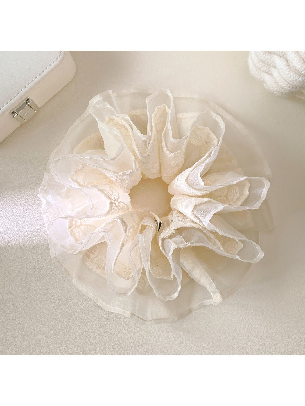 White lace multi-layer scrunchie with delicate floral pattern on a plain background