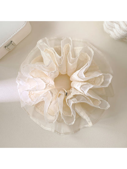 White lace multi-layer scrunchie with delicate floral pattern on a plain background