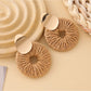 Earedge round drop earrings placed on a textured fabric background