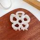 Beau flower shaped hair claw clip packaged in clear plastic box