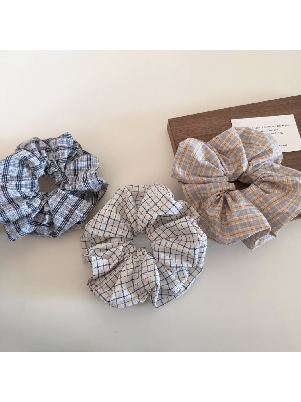 Close-up of Gifty plaid scrunchie with beige and black check pattern on white background