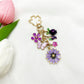 Side view of gold keychain featuring a small daisy flower charm