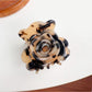 Beau claw clip resting on a wooden surface, highlighting its modern minimalist design