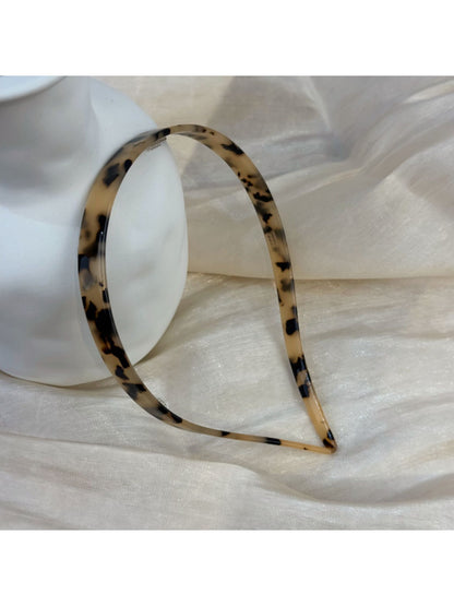 Vintage leopard print hairband displayed on a wooden surface