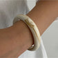 Lovra wide round bangle bracelet angled to show polished metal surface and rounded profile
