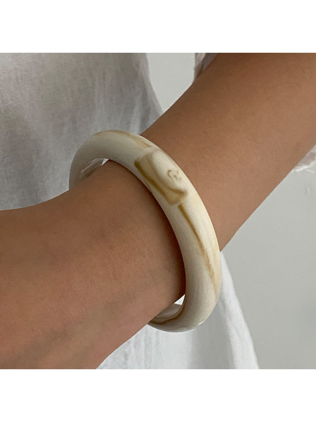 Lovra wide round bangle bracelet angled to show polished metal surface and rounded profile