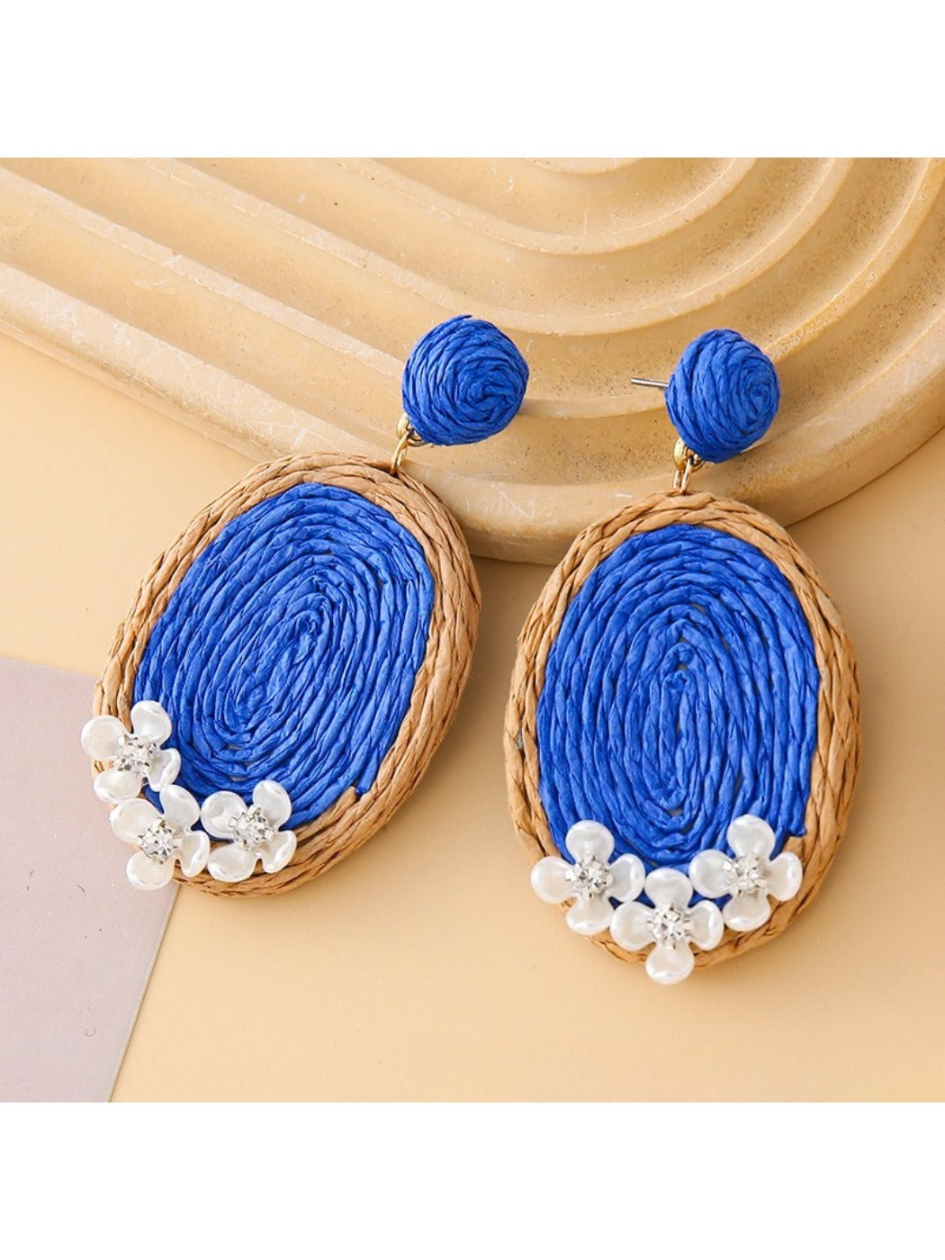 Side view of raffia woven oval earrings showing texture and weave details