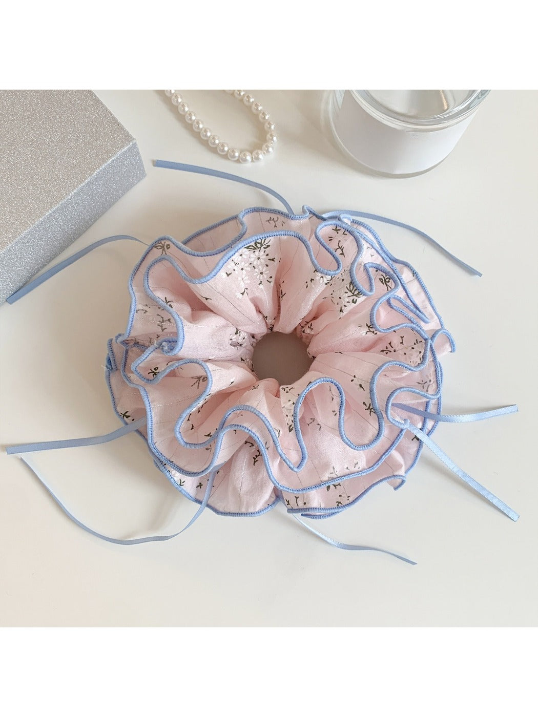 Pink bow print scrunchie stretched to show elastic band inside
