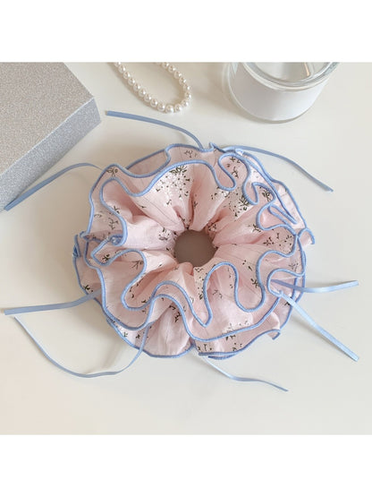 Pink bow print scrunchie stretched to show elastic band inside