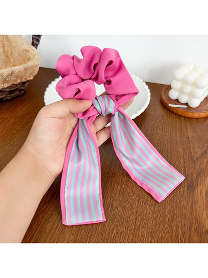 Scrunchie held in hand showing elastic stretch and color pattern