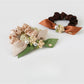 Side view of Gifty hair tie featuring layered fabric flowers in soft pastel colors