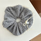White lace bow tie scrunchie wrapped around a wrist as a bracelet