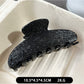 Beau black acetate claw clip displayed on a wooden surface