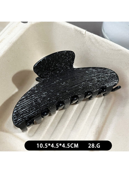 Beau black acetate claw clip displayed on a wooden surface