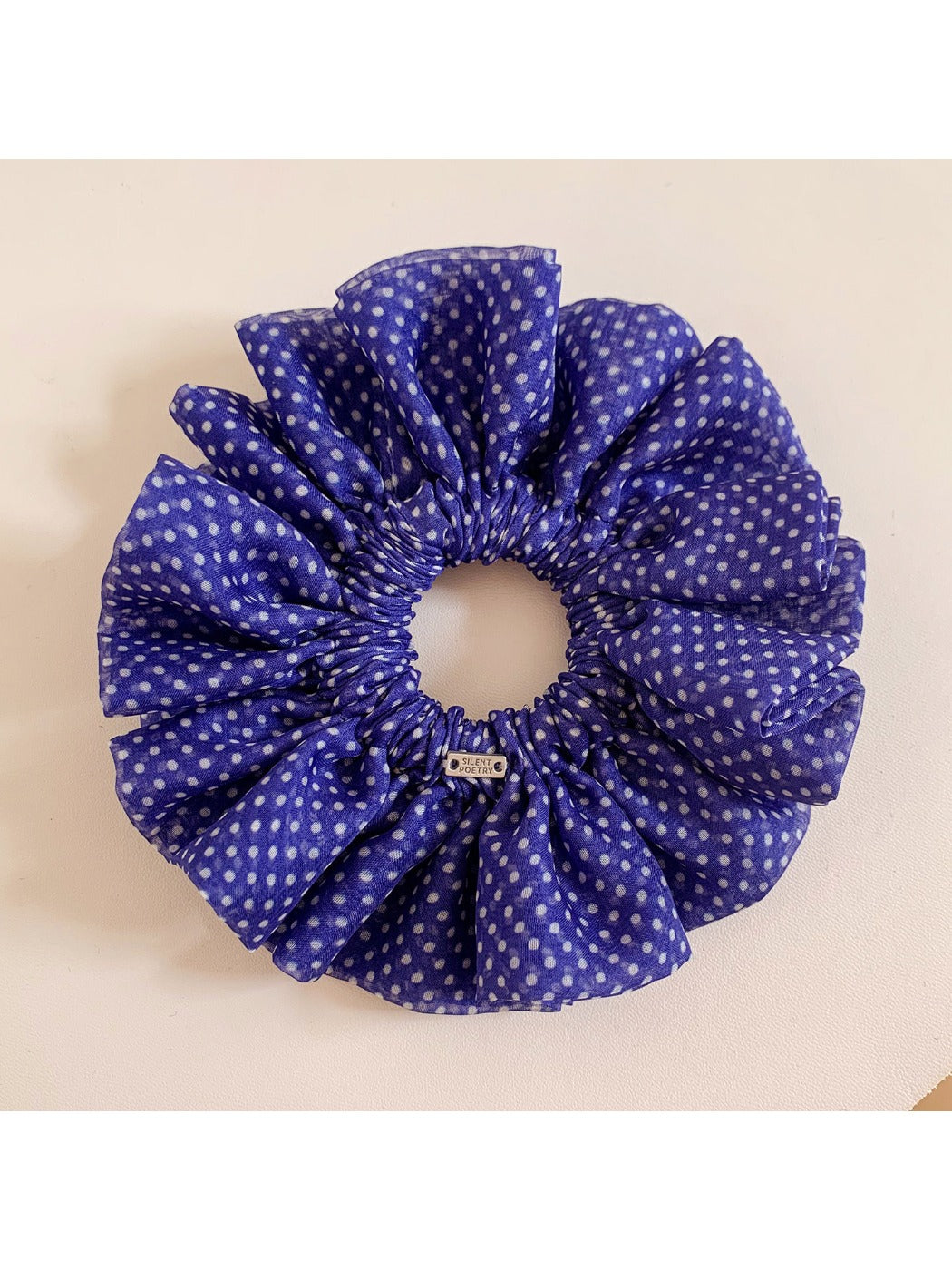 Polka dot ruffled scrunchie stretched slightly to show elasticity and design