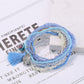 Side view of Lovra multi-row beaded bracelet with tassel on white background