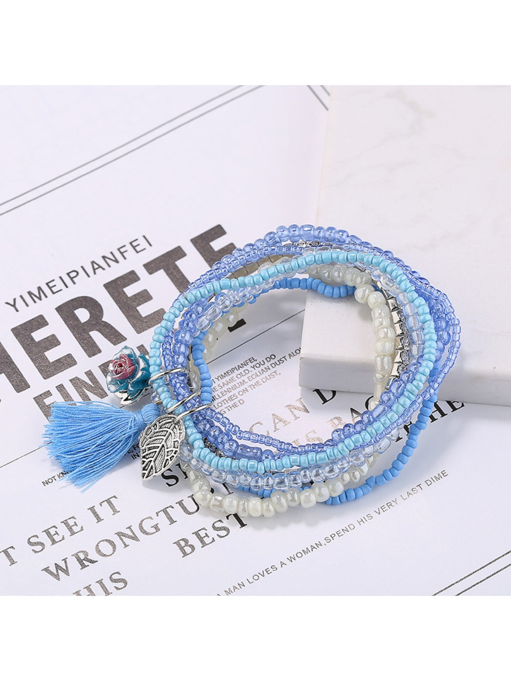 Side view of Lovra multi-row beaded bracelet with tassel on white background
