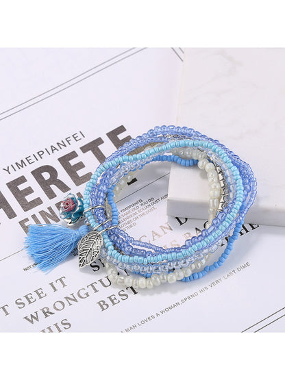 Side view of Lovra multi-row beaded bracelet with tassel on white background