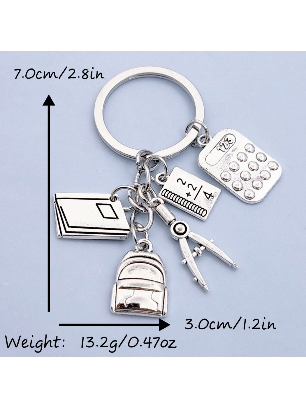Alloy backpack book keychain attached to a set of keys on a wooden surface