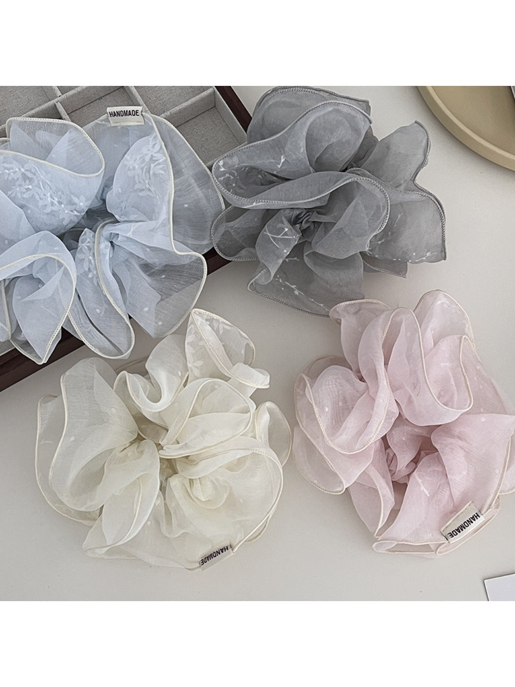 Close-up of Gifty delicate double layer ruffled scrunchie in soft pink fabric