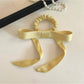 Close-up of Gifty satin yellow ribbon bow scrunchie on white background