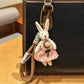 Silver rabbit charm keychain next to a smartphone on a desk