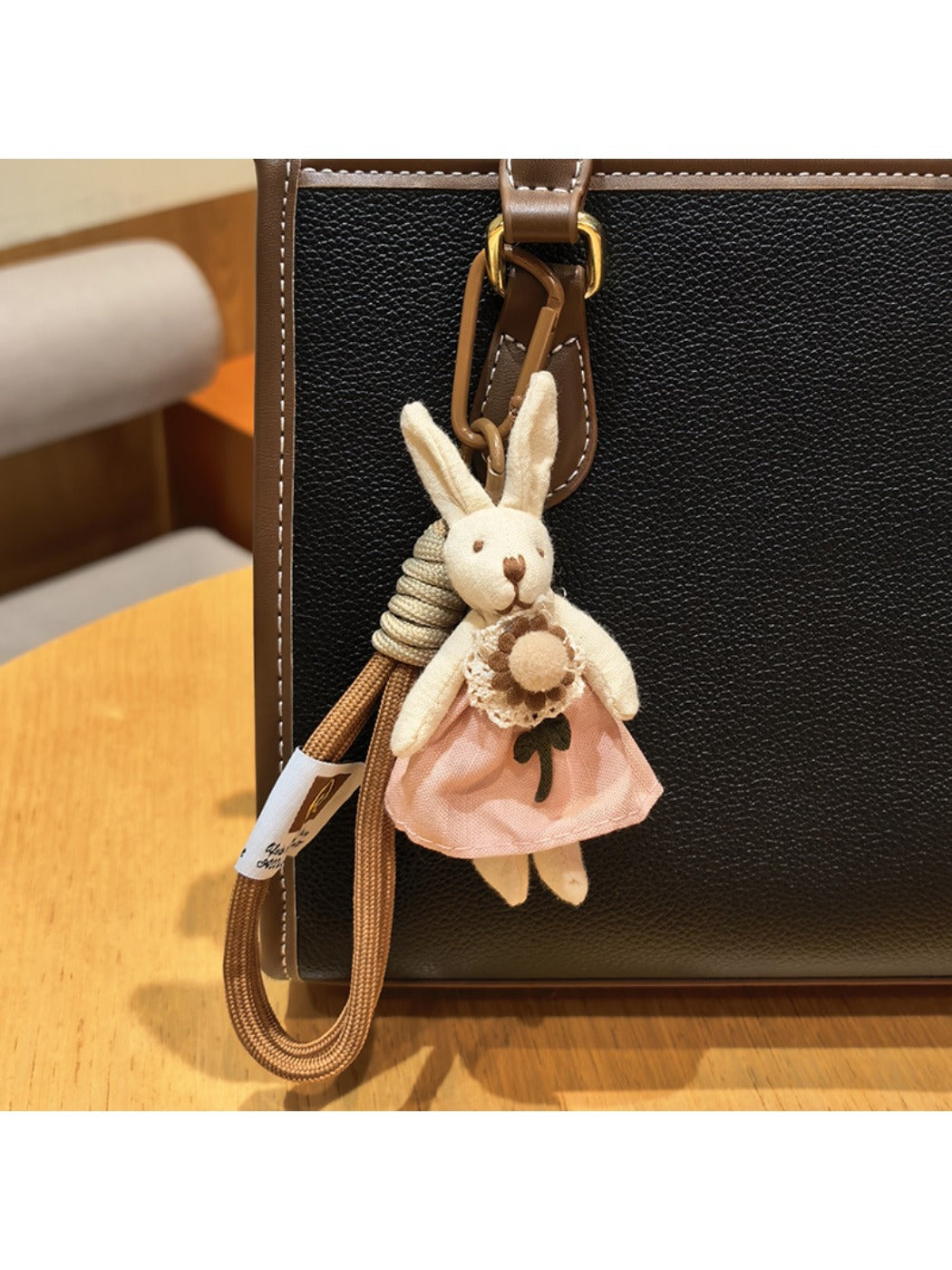 Silver rabbit charm keychain next to a smartphone on a desk