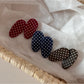 Oval hair clip with white polka dots on a beige background, close-up view