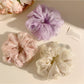 Solid color ruched scrunchie displayed on a wooden surface highlighting fabric texture