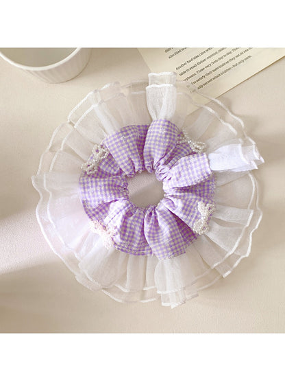 Close-up of Gifty plaid bow scrunchie showing fabric texture and pattern