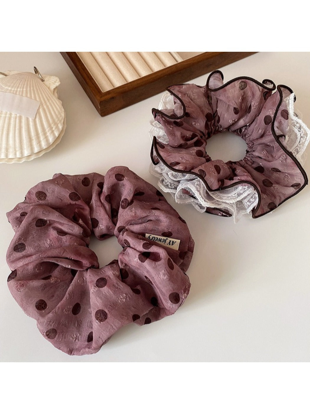 Polka dot ruffled scrunchie worn on a model's wrist with matching headband